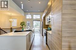 Kitchen featuring an island with sink, stainless steel appliances, modern cabinets, recessed lighting, and decorative light fixtures -