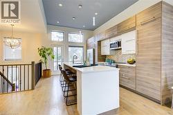 Kitchen featuring white cabinetry, tasteful backsplash, a center island with sink, recessed lighting, and a breakfast bar area -