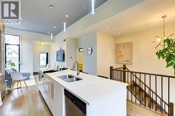 Kitchen with stainless steel dishwasher, pendant lighting, light wood finished floors, a kitchen island with sink, and recessed lighting -