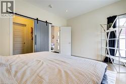Unfurnished bedroom featuring a barn door, wood finished floors, ensuite bathroom, and recessed lighting -