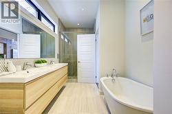 Bathroom with a freestanding tub, a shower stall, double vanity, recessed lighting, and tasteful backsplash -