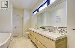 Full bathroom with a freestanding tub, double vanity, decorative backsplash, and recessed lighting -