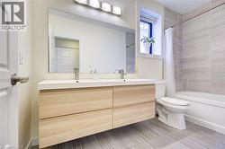Full bath featuring shower / tub combo with curtain and double vanity -