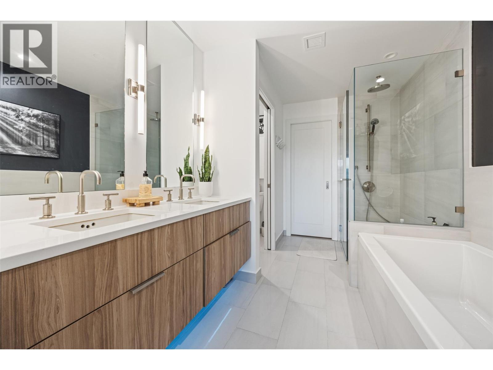 Stunning ensuite with dual vanities, quartz counters, large soaker tub and glass tile shower - 3000 Ariva Drive Unit# 3308, Kelowna, BC - Indoor Photo Showing Bathroom