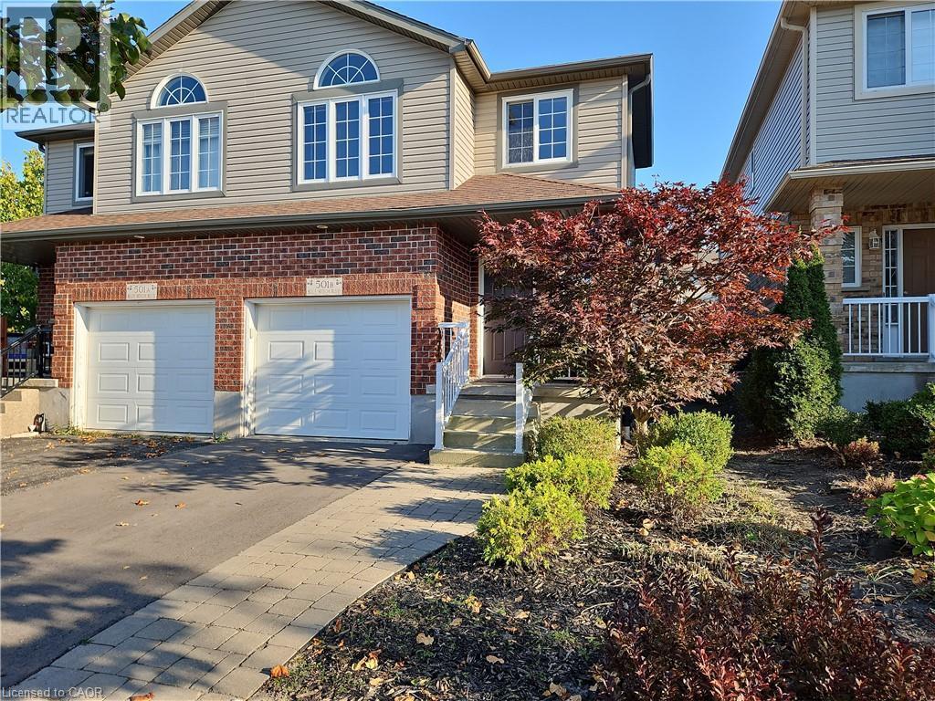 View of front facade featuring driveway, brick siding, a garage, and a shingled roof - 501 Blue Beech Boulevard Unit# B, Waterloo, ON - Outdoor