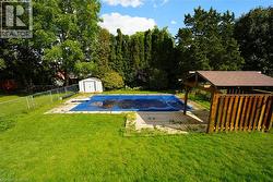 View of basketball court featuring a storage unit, view of scattered trees, and a fenced backyard -