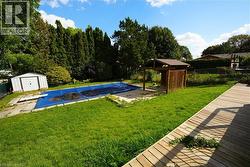 View of pool with a fenced backyard, a storage shed, a diving board, and a patio -