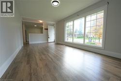 Unfurnished living room featuring wood finished floors and baseboards -