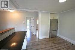 Kitchen featuring freestanding refrigerator, white cabinets, dark wood-style floors, and dark stone countertops -