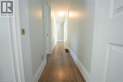 Corridor featuring dark wood-type flooring and baseboards -
