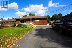View of front facade with brick siding, a front yard, and a chimney -