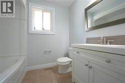 Bathroom with light tile patterned floors, vanity, and a bath -