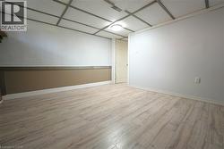 Empty room with light wood-style floors and a drop ceiling -