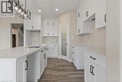 Kitchen with white cabinets, recessed lighting, a center island with sink, dark wood finished floors, and decorative light fixtures -