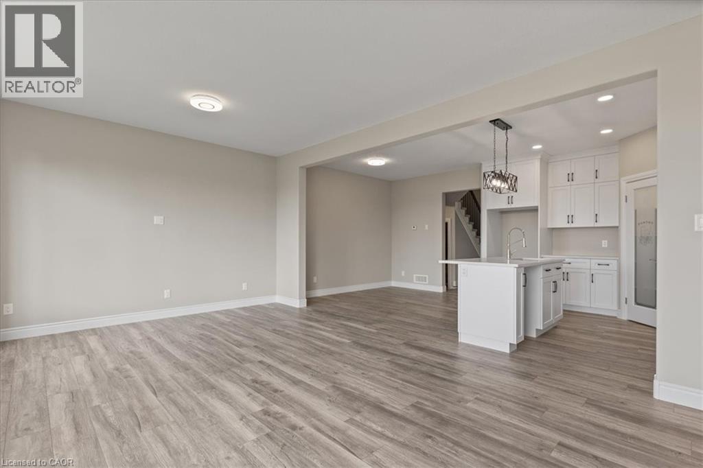 Unfurnished living room with light wood-style flooring, recessed lighting, a chandelier, and stairs - 256 Keeso Lane, Listowel, ON - Indoor Photo Showing Kitchen