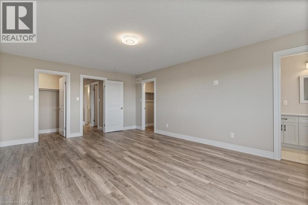 Unfurnished bedroom featuring light wood finished floors, a spacious closet, and connected bathroom - 256 Keeso Lane, Listowel, ON - Indoor Photo Showing Other Room