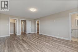 Unfurnished bedroom featuring light wood finished floors, a spacious closet, and connected bathroom -