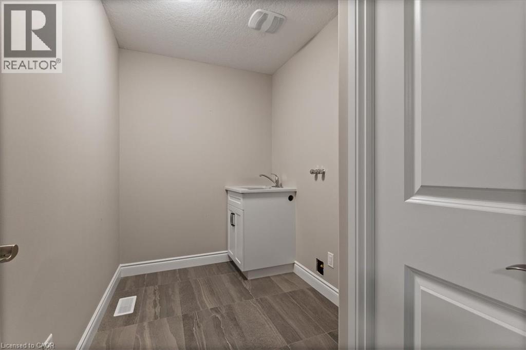 Washroom featuring a textured ceiling, hookup for a washing machine, and cabinet space - 256 Keeso Lane, Listowel, ON - Indoor Photo Showing Other Room