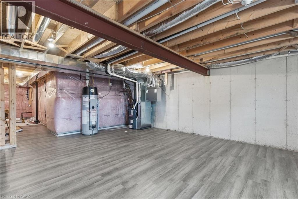 Unfinished basement featuring gas water heater, wood finished floors, and heating unit - 256 Keeso Lane, Listowel, ON - Indoor Photo Showing Basement