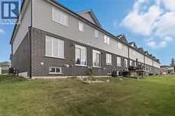 Back of house featuring brick siding and a yard -