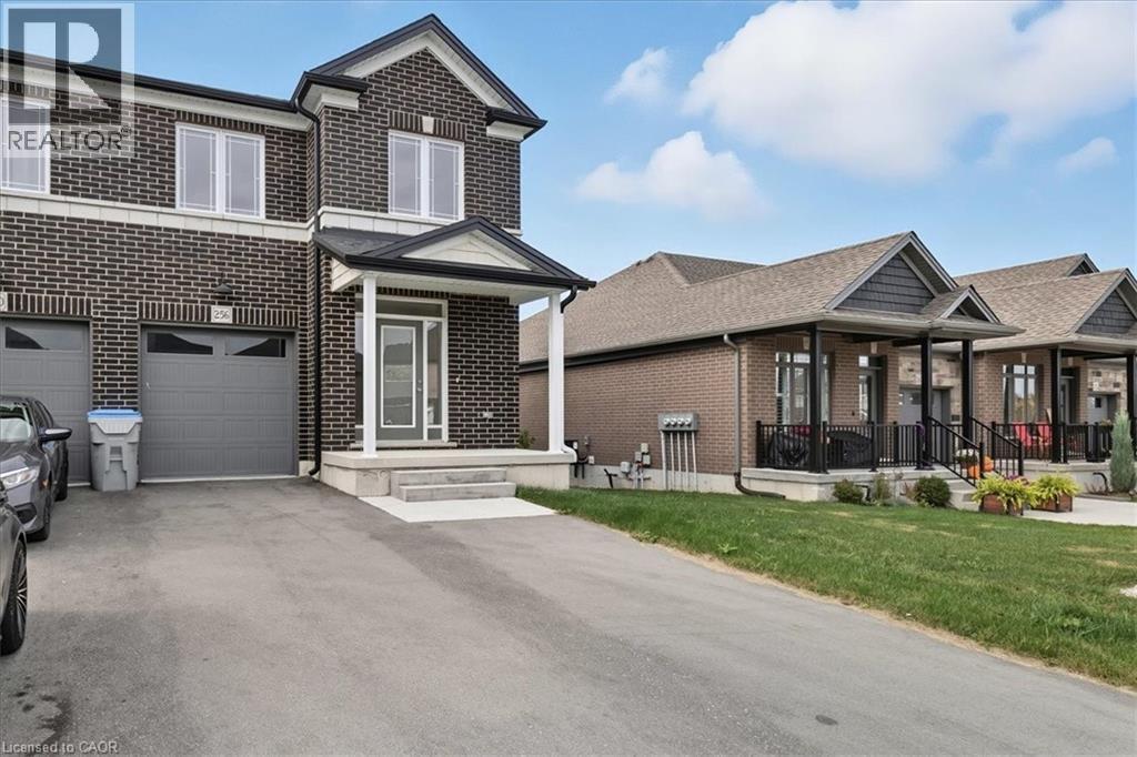View of front facade featuring brick siding, asphalt driveway, a front lawn, a porch, and an attached garage - 256 Keeso Lane, Listowel, ON - Outdoor With Facade