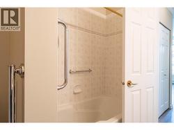 full tub with shower and grab bars as well as nice tiling. -