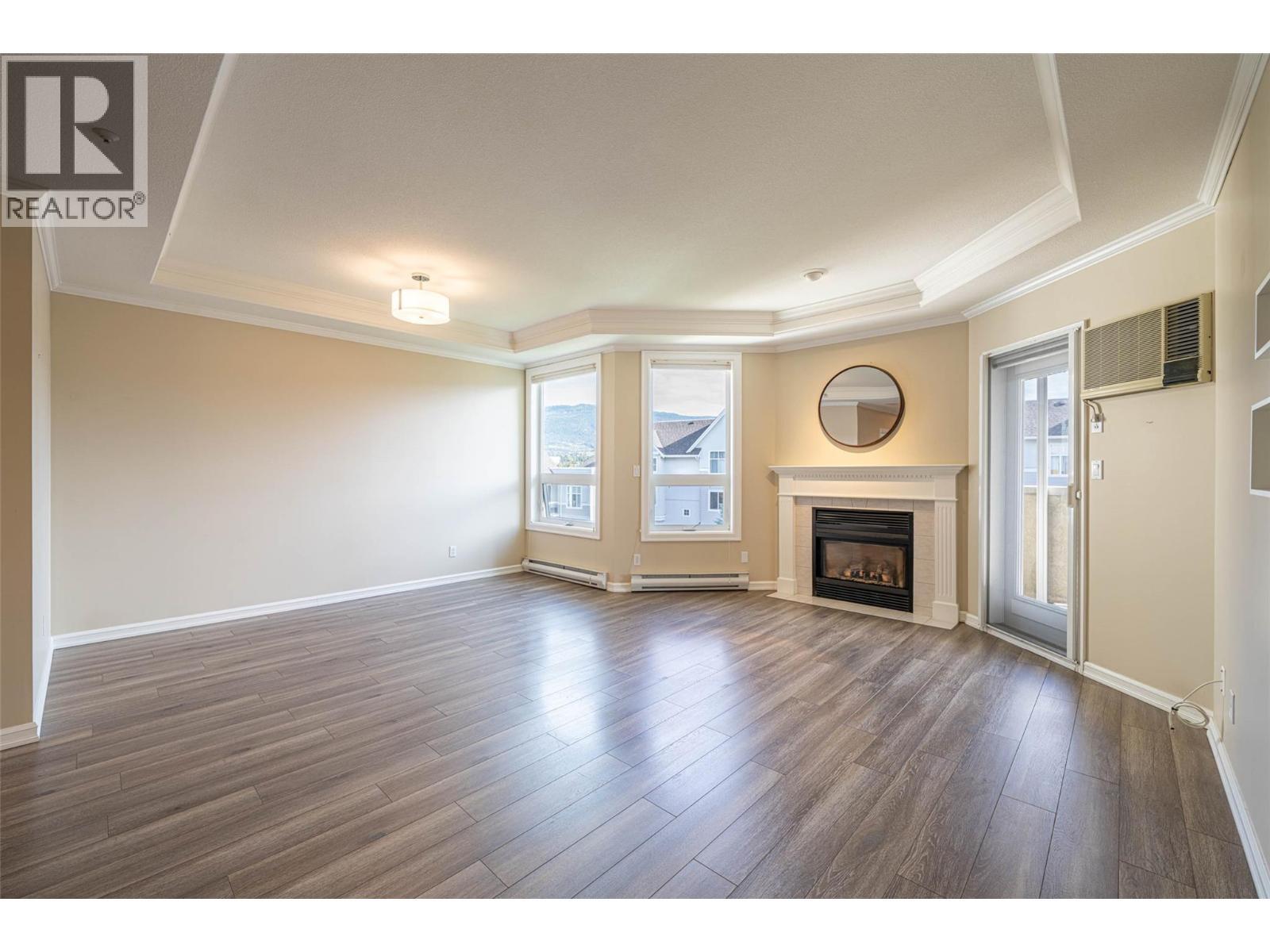Living Room with 9 ft ceilings, cozy gas fireplace & french doors to lovely covered balcony - 3300 Centennial Drive Unit# 411, Vernon, BC - Indoor Photo Showing Living Room With Fireplace