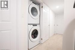 Washroom with light carpet and stacked washing machine and dryer -