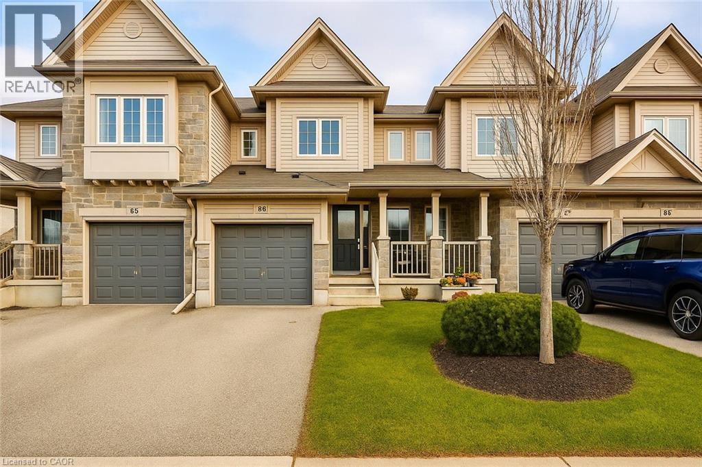 View of front of home featuring stone siding, a front yard, covered porch, driveway, and a garage - 6 Upper Mercer Street Unit# B6, Kitchener, ON - Outdoor With Facade
