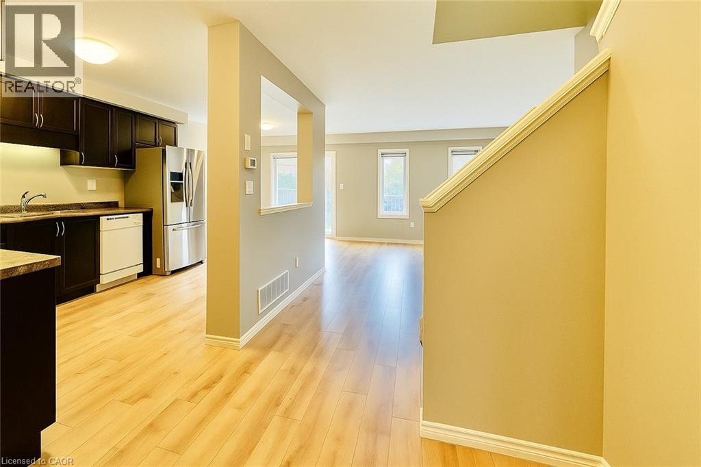 Kitchen featuring light wood-style flooring, white dishwasher, dark countertops, dark brown cabinets, and stainless steel refrigerator with ice dispenser - 6 Upper Mercer Street Unit# B6, Kitchener, ON - Indoor Photo Showing Kitchen