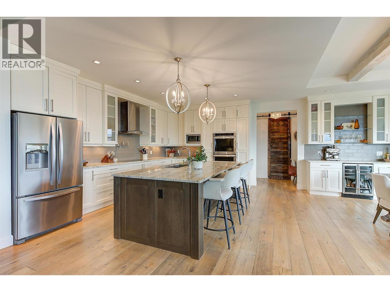 Open, bright kitchen with a large sit-up island featuring rich dark cabinetry and a beautiful granite countertop - 738 Highpointe Drive, Kelowna, BC - Indoor Photo Showing Kitchen With Upgraded Kitchen