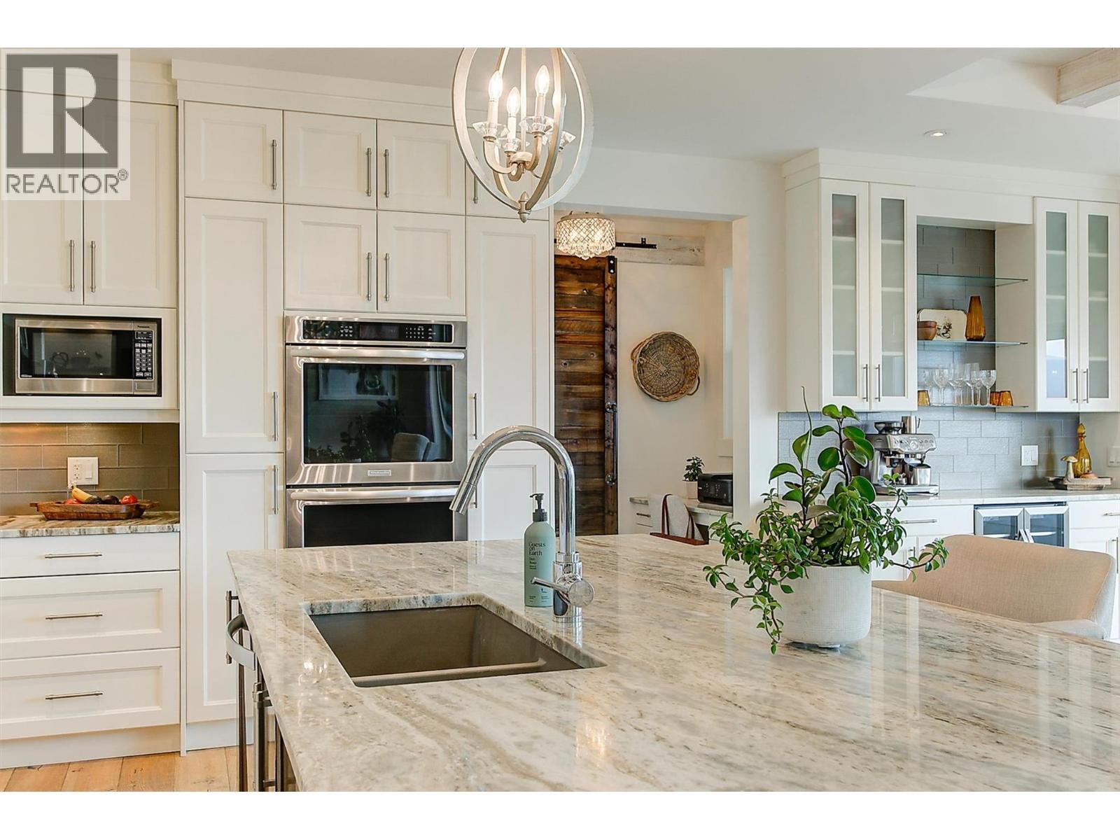 The modern kitchen includes highend SS appliances: Whirlpool fridge, KitchenAid induction glass cooktop with pot filler, Whirlpool dishwasher, KitchenAid dual ovens & Panasonic microwave. - 738 Highpointe Drive, Kelowna, BC - Indoor Photo Showing Kitchen With Double Sink With Upgraded Kitchen