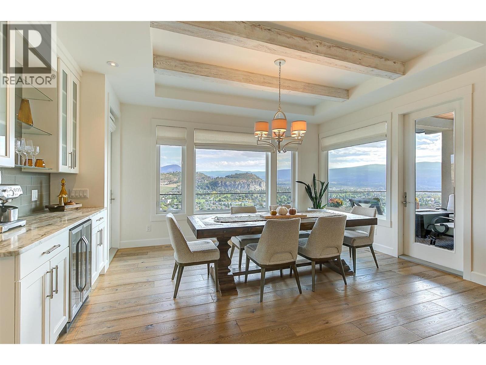 The dining space for 8-10ppl features wood beams, designer lighting and a built-in beverage centre with bar fridge - 738 Highpointe Drive, Kelowna, BC - Indoor Photo Showing Dining Room