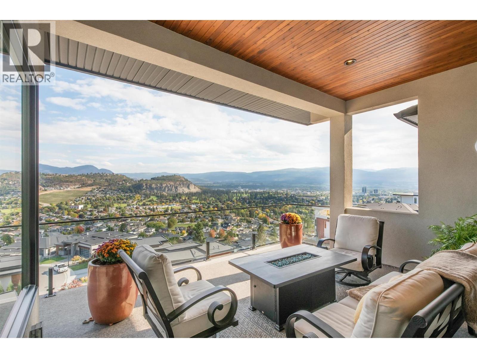 The main level covered deck features a glass railing, spacious outdoor living area - 738 Highpointe Drive, Kelowna, BC - Outdoor With Deck Patio Veranda With View With Exterior