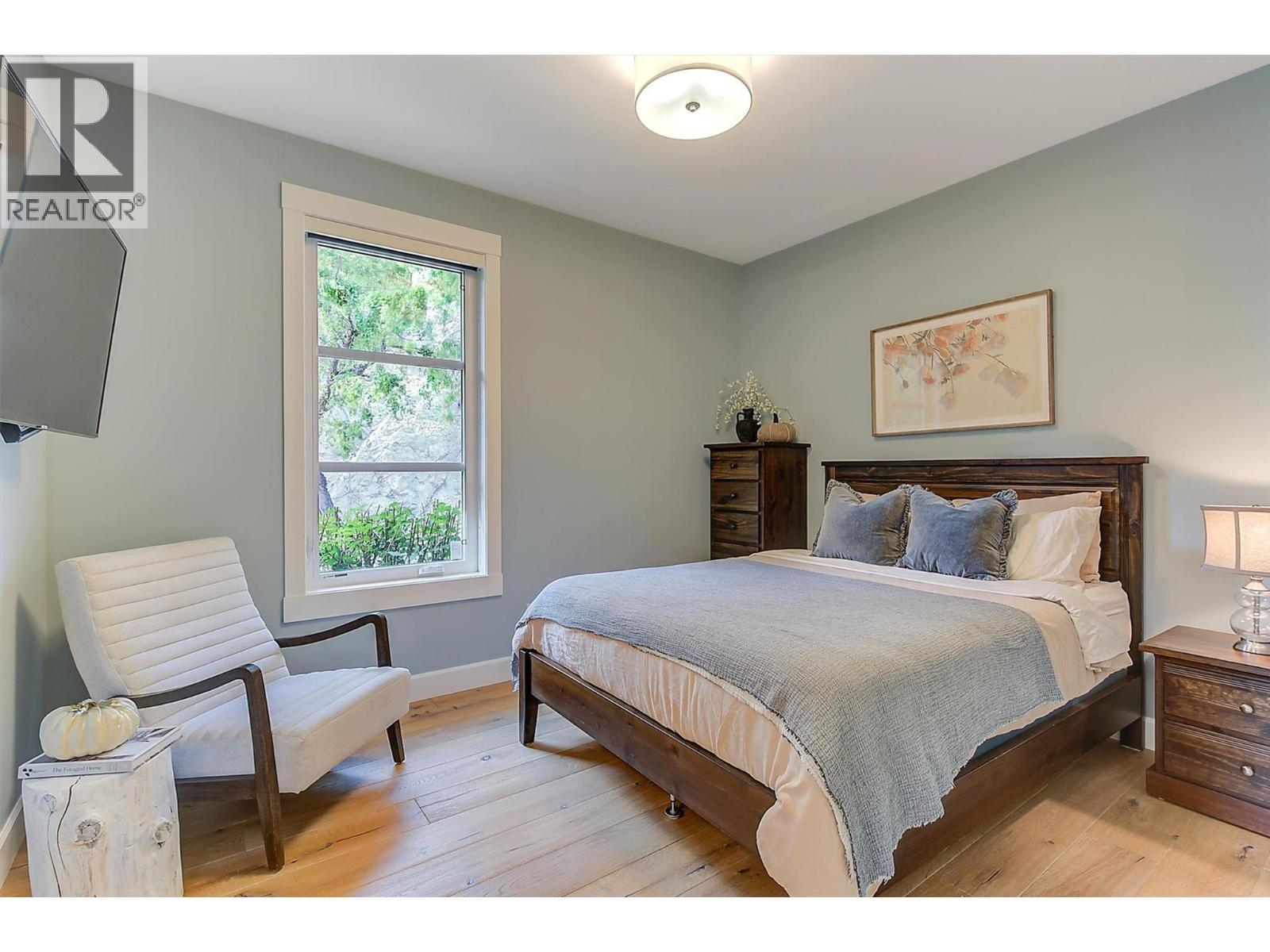 Guest bedroom on the main level features a queen-size layout, streetscape views, a two-door closet - 738 Highpointe Drive, Kelowna, BC - Indoor Photo Showing Bedroom
