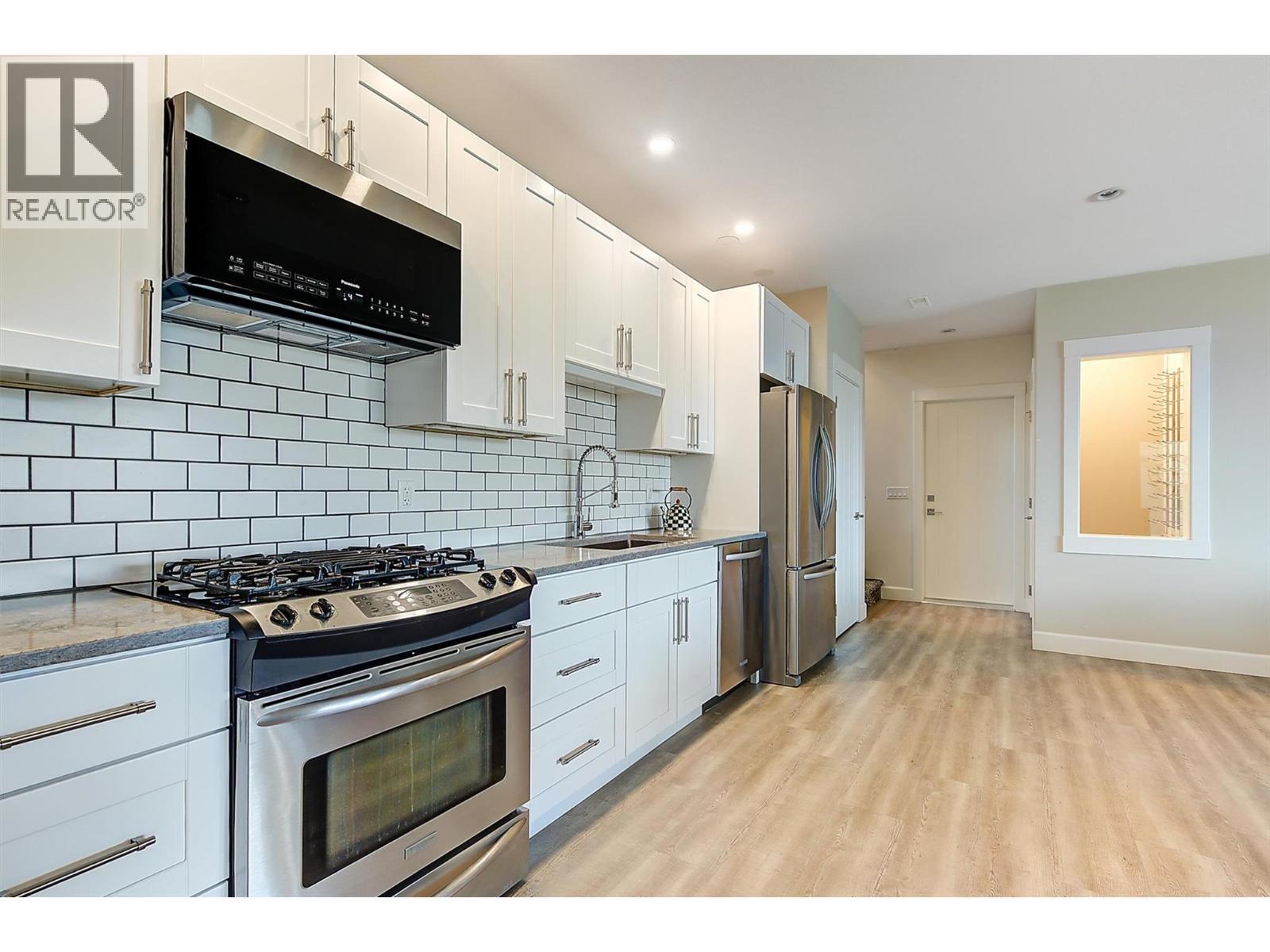 A secondary kitchen features sleek SS appliances and wine room. - 738 Highpointe Drive, Kelowna, BC - Indoor Photo Showing Kitchen With Upgraded Kitchen