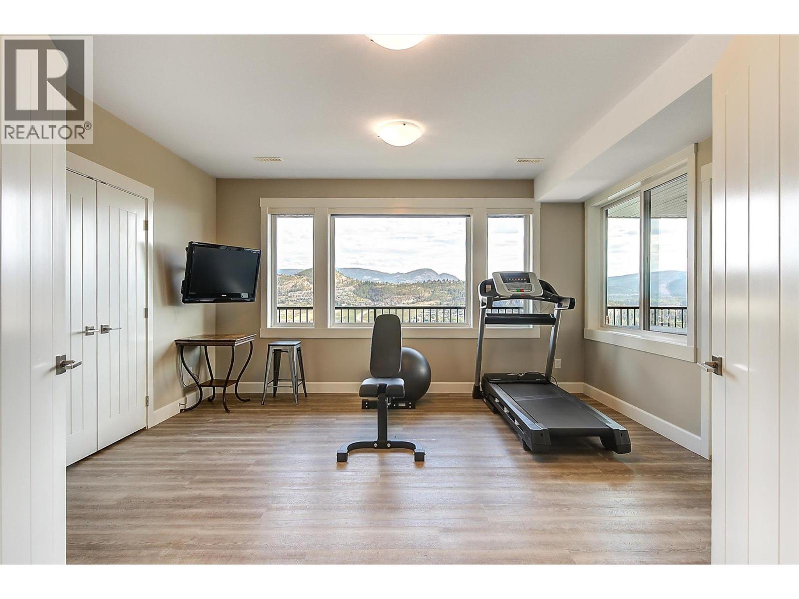 A large, flex space currently used as a gym with a dual door entry, a large closet and opens to the outdoor living space & pool. - 738 Highpointe Drive, Kelowna, BC - Indoor Photo Showing Gym Room