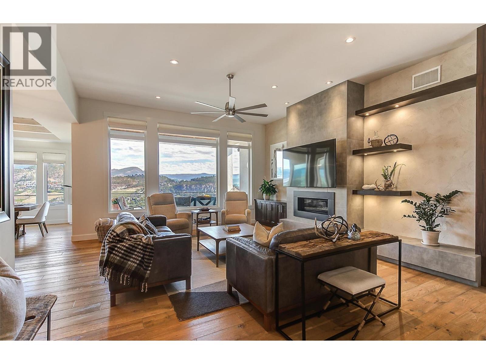 Wall of windows flood this space with natural light - 738 Highpointe Drive, Kelowna, BC - Indoor Photo Showing Living Room With Fireplace