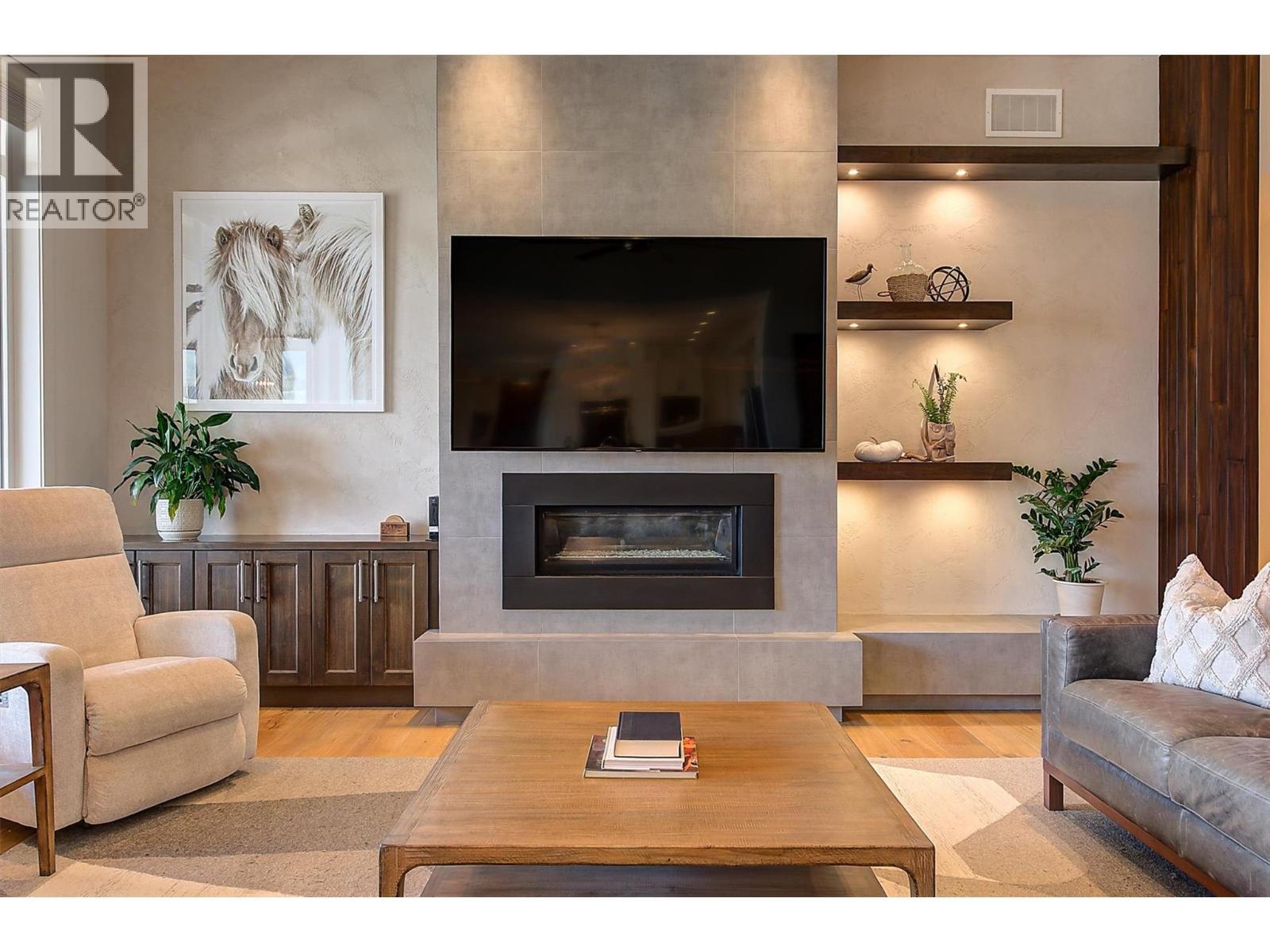 A fireplace anchors the room, finished in light grey large-format tile - 738 Highpointe Drive, Kelowna, BC - Indoor Photo Showing Living Room With Fireplace