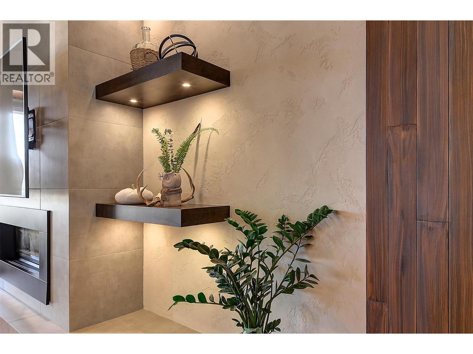 Complemented by floating dark wood shelves and built-in millwork - 738 Highpointe Drive, Kelowna, BC - Indoor Photo Showing Other Room
