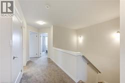 Hallway featuring carpet and an upstairs landing -