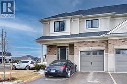 View of front of home featuring roof with shingles, brick siding, driveway, and a garage -