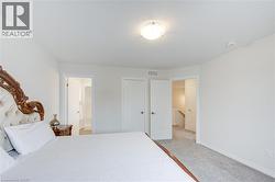 Bedroom with light colored carpet, a closet, and ensuite bathroom -