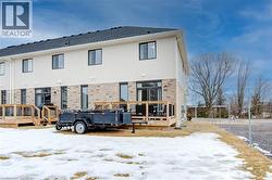 Snow covered house featuring a wooden deck and brick siding -