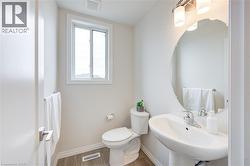 Half bathroom with toilet and wood finished floors -