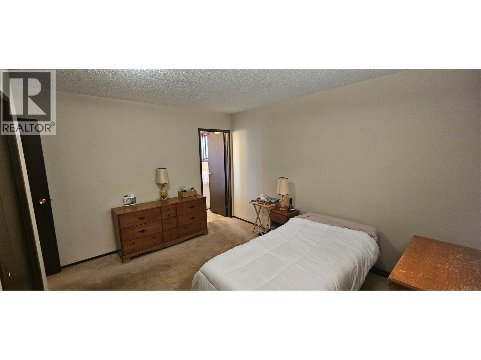 Primary bedroom with the ensuite door visible - 1234 Hickory Crescent, Sparwood, BC - Indoor Photo Showing Bedroom