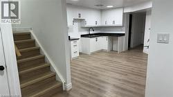 Kitchen with dark countertops, light wood finished floors, and white cabinetry -