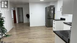 Kitchen featuring dark countertops, white cabinets, freestanding refrigerator, light wood-type flooring, and recessed lighting -