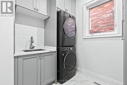 Main Laundry with sink and stacked washer/dryer -