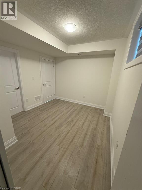 Unfurnished bedroom featuring light wood-style flooring and a textured ceiling - 347 Canada Plum Street Unit# Lower, Waterloo, ON - Indoor Photo Showing Other Room